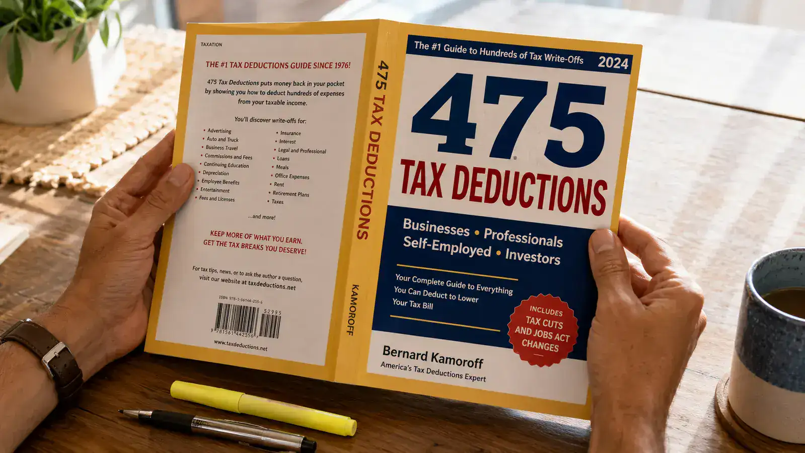 Hand holding the 475 Tax Deductions book open to a page with highlighted entries and a pen nearby