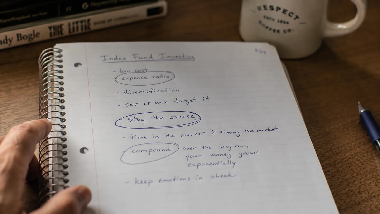 A notebook open to a handwritten page with the words index fund, expense ratio, and stay the course circled in pen