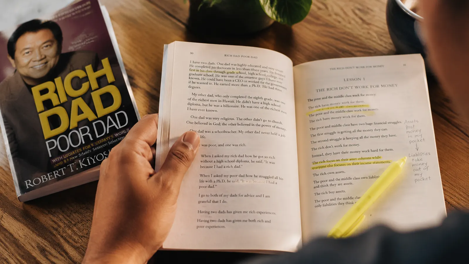 Worn copy of Rich Dad Poor Dad with handwritten margin notes and a highlighter resting on top